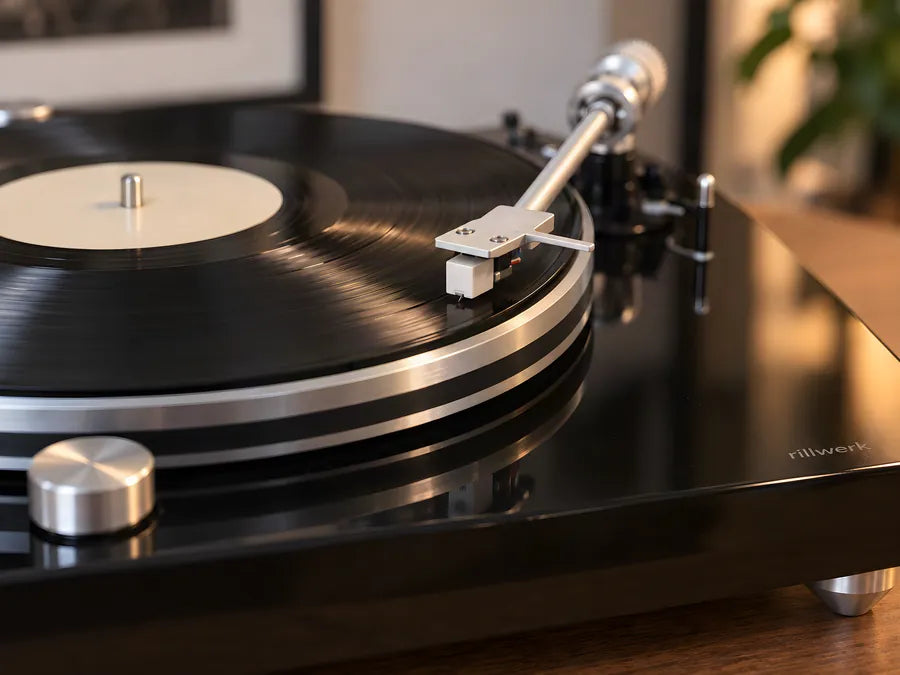 Close-up: the silver tonearm with a white cartridge resting in the groove of a record